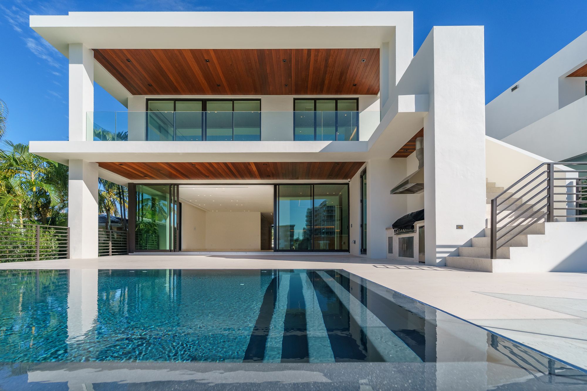 Vista ampla de uma casa contemporânea de dois pavimentos, com fachada envidraçada, madeira e piscina